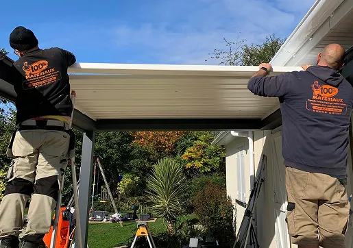 Deux artisans installent une structure en bois sous un abri extérieur à Normanville