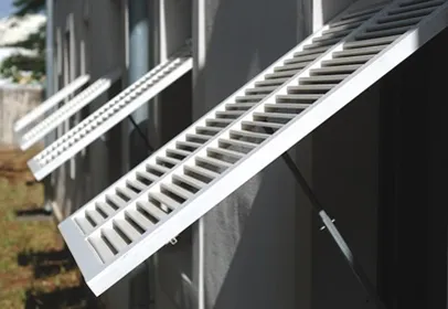 Volets persiennes en aluminium à lames ajourées sur une façade sombre