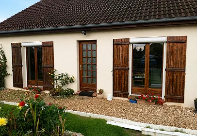 Maison normande avec menuiserie bois extérieure et jardin fleuri devant façade claire