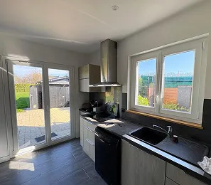 Cuisine moderne avec baie vitrée donnant sur jardin à Normanville