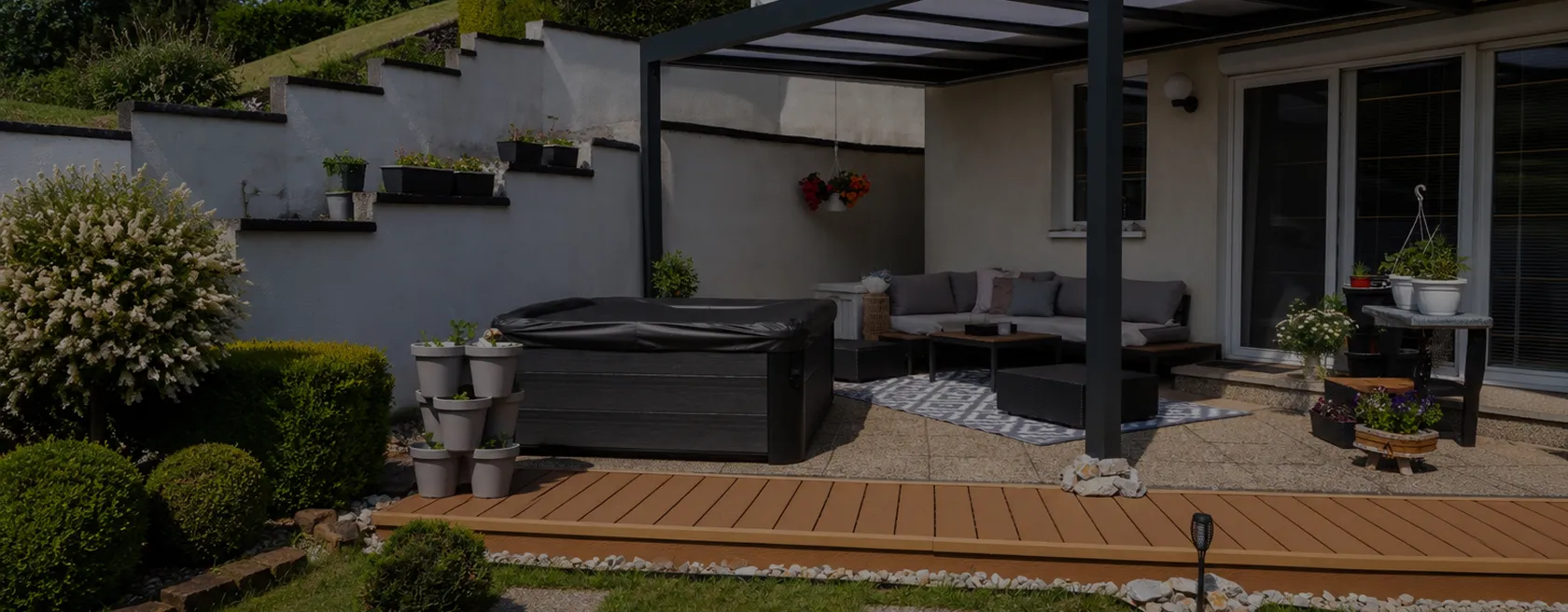 Terrasse bois avec salon extérieur et plantes sous pergola moderne